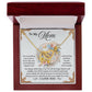 The Mom-Taught Me - Interlocking Hearts Necklace, finished in rose gold and shimmering with cubic zirconia crystals, is presented in an open red box. The background card features a heartfelt message for "Mom," thanking her for her support and sacrifices, beautifully adorned with floral accents.