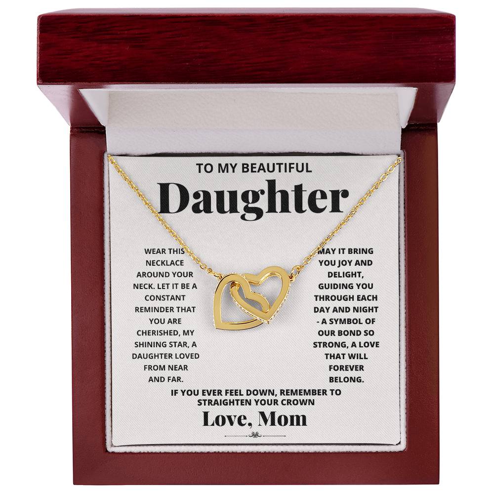 A "To My Daughter, Wear This Necklace - Interlocking Hearts Necklace" with interlocking heart pendants adorned with cubic zirconia crystals on a printed message card from a mother to her daughter, expressing love and encouragement.
