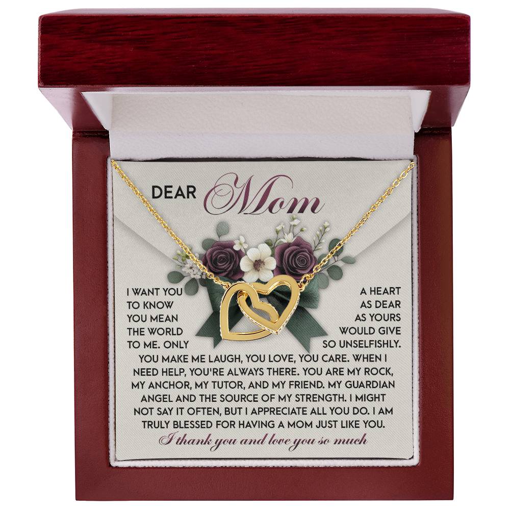 The Mom-Guardian Angel - Interlocking Hearts Necklace, featuring cubic zirconia crystals, rests in a jewelry box on a floral-themed "Dear Mom" card. It beautifully conveys gratitude and love for a mother's unwavering care, making it the perfect gift for her.
