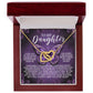 The Daughter-Moon Back - Interlocking Hearts Necklace, with a rose gold finish and sparkling cubic zirconia crystals, is elegantly displayed in an open wooden box. The box’s interior features a touching message to a daughter, framed by floral designs on a purple backdrop.
