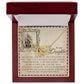 A Daughter-Withstand Storm Interlocking Hearts Necklace in an 18k yellow gold finish lies in a red velvet-lined box. The cubic zirconia-adorned pendant comes with a heartfelt ship illustration and words of courage and strength for your daughter.