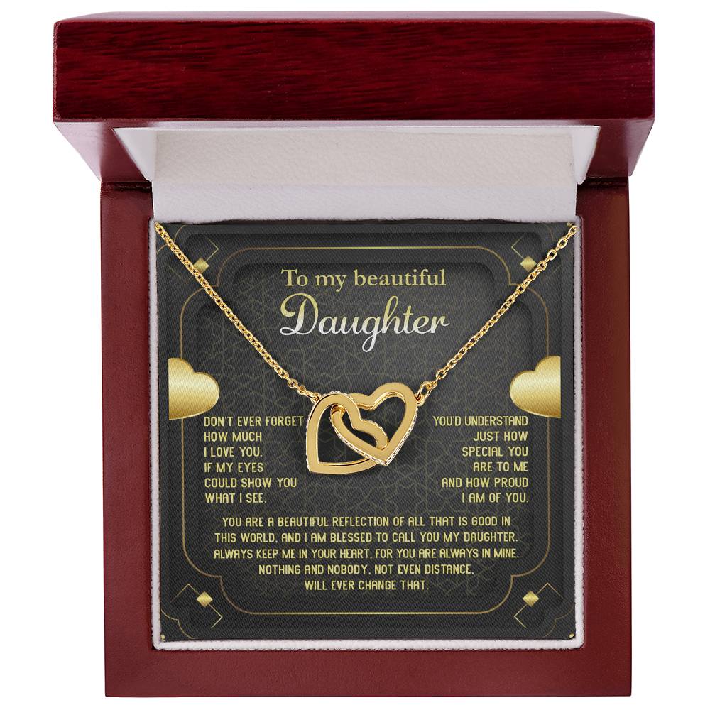 The "To Daughter, Beautiful Reflection - Interlocking Hearts Necklace" features an 18k yellow gold finish and is presented on a card that conveys a heartfelt message of love, pride, and eternal connection. The interlocking hearts are adorned with sparkling cubic zirconia crystals.