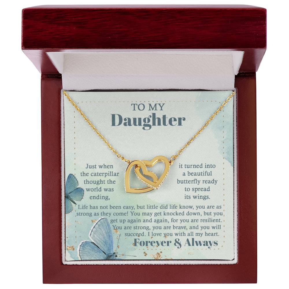 The "To Daughter, Beautiful Butterfly - Interlocking Hearts Necklace" is beautifully presented in a box adorned with blue butterflies and motivational messages about resilience and love. Sparkling with cubic zirconia crystals, this adjustable-length necklace ensures a perfect fit, making it a treasured keepsake for your daughter.