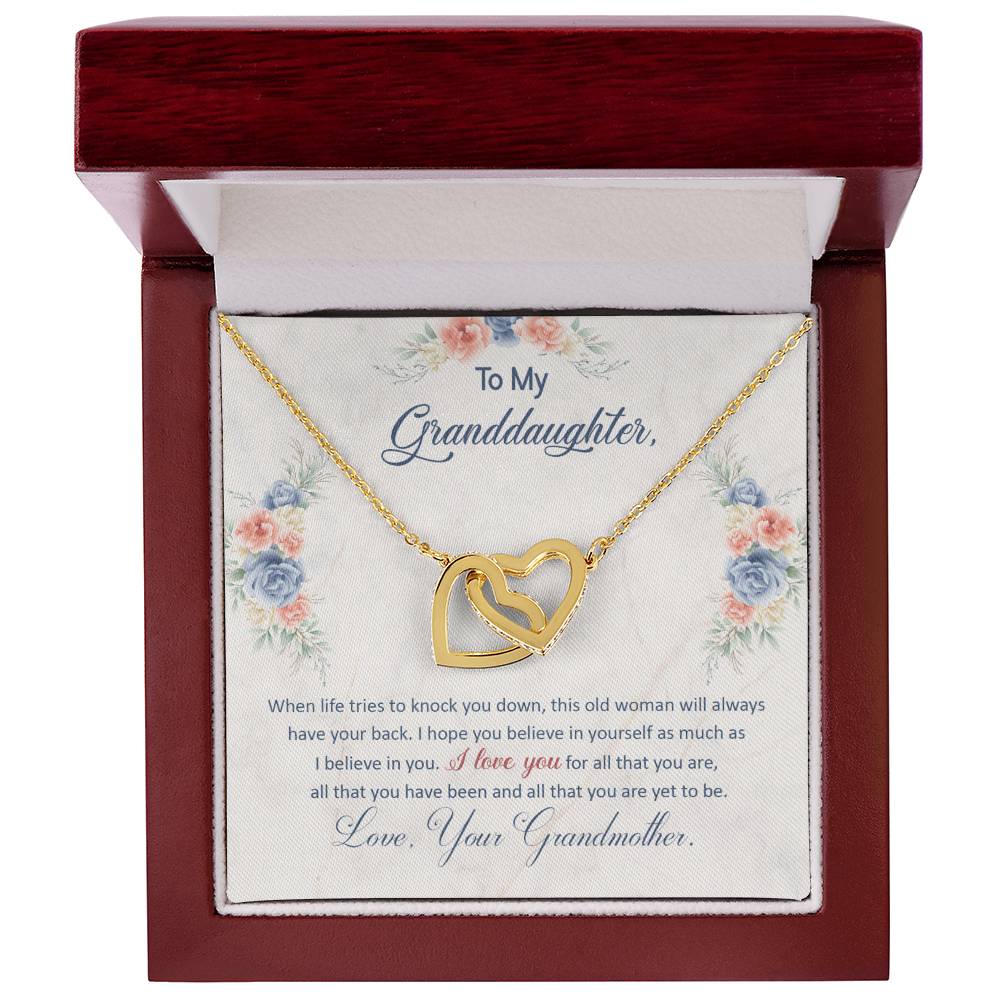 A "To My Granddaughter, This Old Woman Will Always Have Your Back - Interlocking Hearts Necklace" from ShineOn Fulfillment inside a gift box with an affectionate message from a grandmother to her granddaughter.