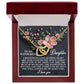 A jewelry box displays the Daughter-Love Sight - Interlocking Hearts Necklace in a rose gold finish. Pink flowers and a message expressing love and happiness to a daughter serve as the backdrop, ending with "I love you.