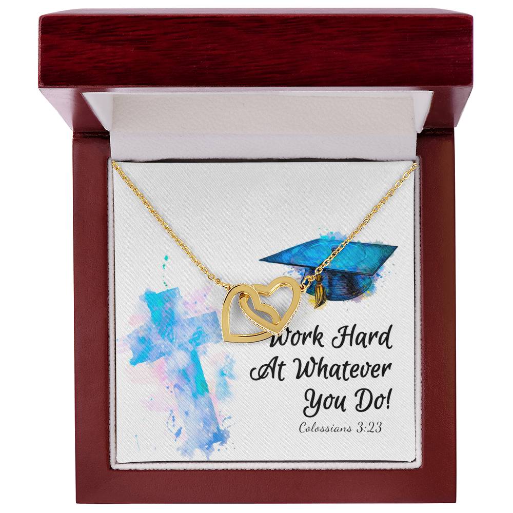 A Work Hard - Interlocking Hearts Necklace from ShineOn Fulfillment, with a graduation cap pendant adorned with cubic zirconia crystals, presented in a gift box featuring an inspirational message and a biblical verse reference.