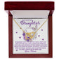 A jewelry box displays the Daughter-Angel Heart - Interlocking Hearts Necklace in rose gold, sparkling with cubic zirconia. The card says, "To my beautiful daughter... Love, Mom," against a backdrop of purple butterflies and floral accents.