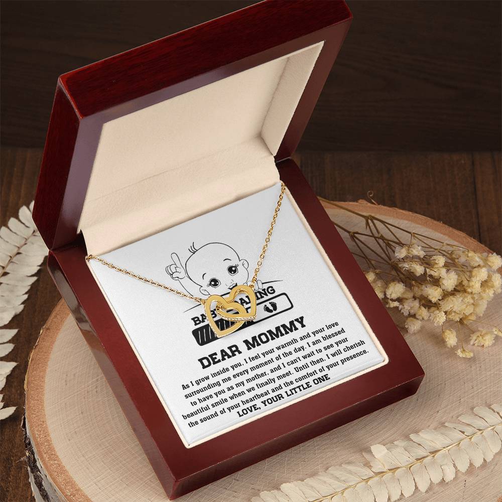 An ShineOn Fulfillment Interlocking Hearts necklace with a pendant featuring a printed message and illustration, presented in a red gift box on a wooden surface.
