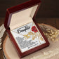 An open wooden box reveals a Daughter-Journey Challenges Interlocking Hearts Necklace in a rose gold finish. The lid displays a heartfelt message for a daughter with a red rose illustration, set against a wooden background with dried flowers to highlight the necklace's elegance.