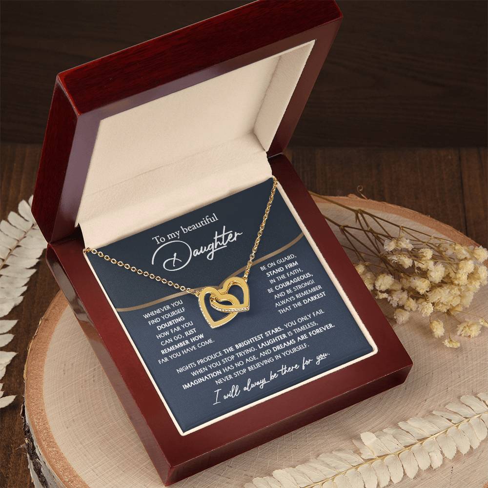 The "To Daughter, Brightest Stars - Interlocking Hearts Necklace," crafted from high-quality polished surgical steel and adorned with cubic zirconia crystals, is presented on a message card addressed to a daughter, offering encouraging and motivational words.