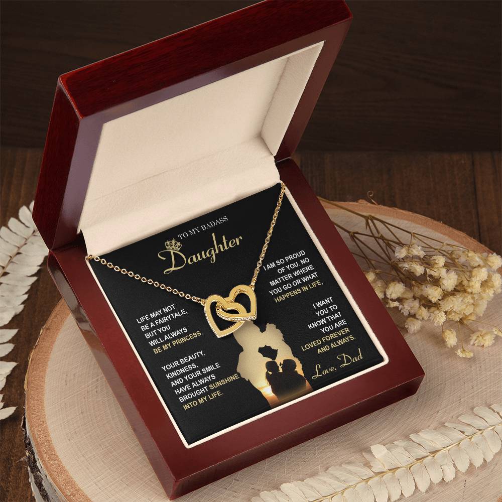 The "To Daughter, Be My Princess - Interlocking Hearts Necklace" with a rose gold finish and adorned with cubic zirconia crystals is displayed in a box that features a heartfelt message from a father to his daughter about love, support, and pride. The text and silhouette of a father and daughter are also included below.