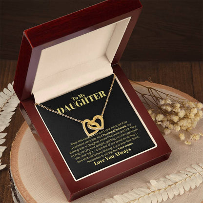 The "[Almost Sold Out] To My Daughter, Wear This Necklace - Interlocking Hearts Necklace" features cubic zirconia crystals symbolizing eternal love, nestled in a gift box with a heartfelt message to a daughter, surrounded by dried flowers on a wooden surface.
