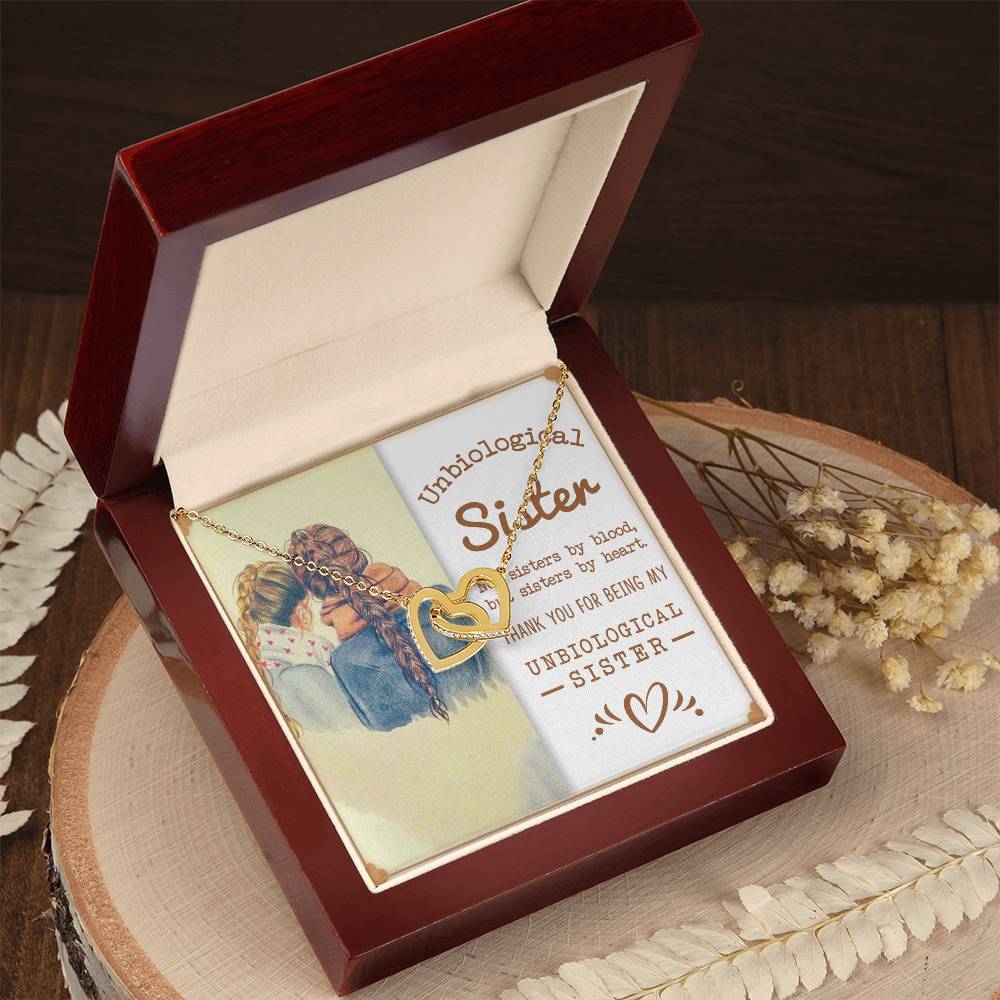 A necklace with a heartfelt message for a sister, presented in a To My Unbiological Sister, Sisters By Heart - Interlocking Hearts Necklace design in a gift box from ShineOn Fulfillment.