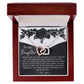 The Daughter-Better Person Interlocking Hearts Necklace, featuring cubic zirconia crystals, rests in an open polished wood jewelry box. The lid displays a floral "To my Daughter" message, and it features an elegant white and black interior.