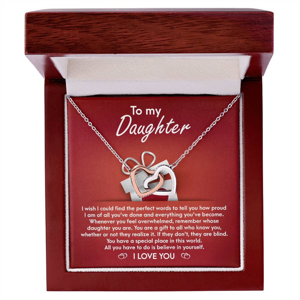 A stunning "To Daughter, A Gift - Interlocking Hearts Necklace" with cubic zirconia crystals is displayed on a red card, featuring a heartfelt message for a daughter, expressing pride, love, and encouragement.