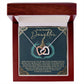 The Daughter-Little Princess Interlocking Hearts Necklace features silver and rose gold pendants with sparkling cubic zirconia. It comes in a wooden box with an inside lid carrying a heartfelt message to a daughter, expressing love, pride, and admiration.