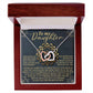 The Daughter-Reach Stars - Interlocking Hearts Necklace features a heart-shaped pendant with cubic zirconia, an 18k yellow gold finish, and comes in a wooden box. The lid says "To my Daughter," with an engraved heartfelt message inside.