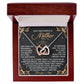 A jewelry box features the Mom-God’s Masterpiece - Interlocking Hearts Necklace in rose gold. The lid reveals an inscription celebrating a mother as "God's Masterpiece," accented by sparkling cubic zirconia crystals for added elegance.
