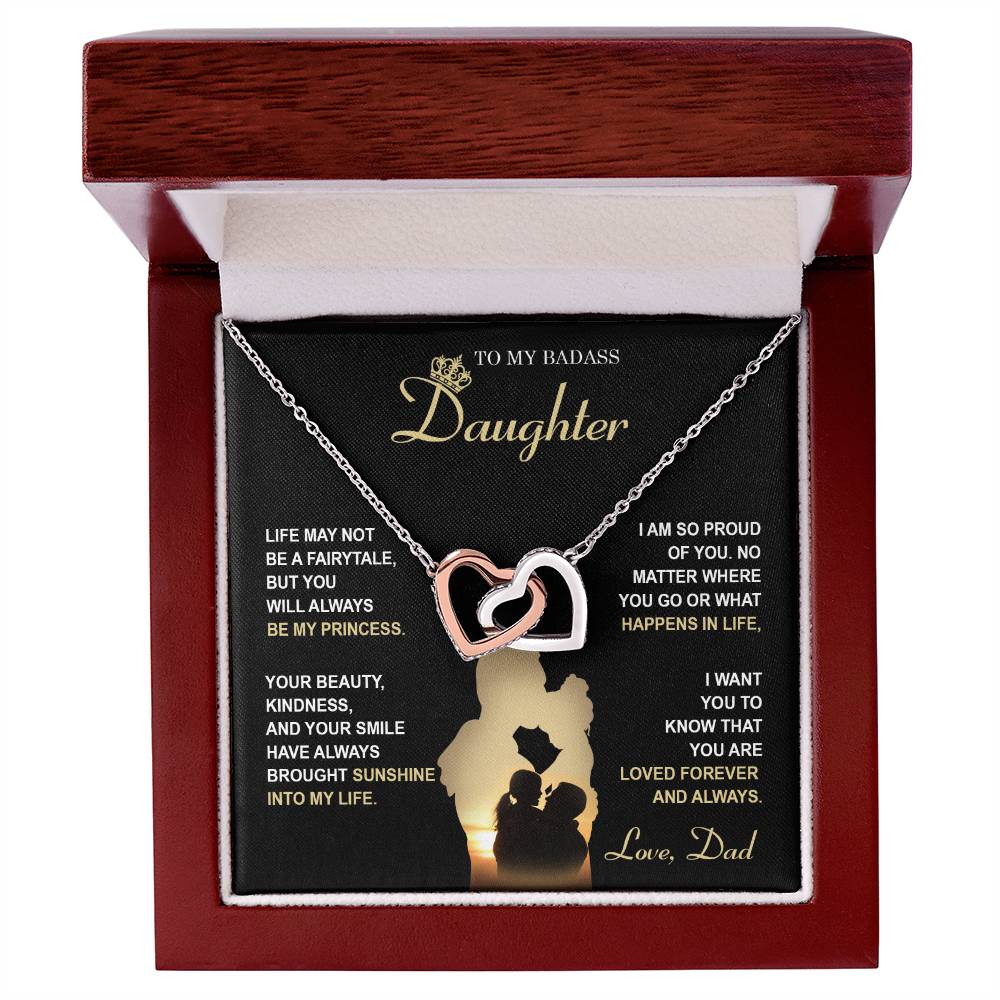 The "To Daughter, Be My Princess - Interlocking Hearts Necklace" with a rose gold finish and adorned with cubic zirconia crystals is displayed in a box that features a heartfelt message from a father to his daughter about love, support, and pride. The text and silhouette of a father and daughter are also included below.