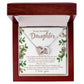 The Daughter-First Smile Interlocking Hearts Necklace, adorned with cubic zirconia crystals, arrives in a wooden box. Inside the lid, surrounded by floral decorations, is the heartfelt message "To my beautiful Daughter," celebrating love, strength, and grace.