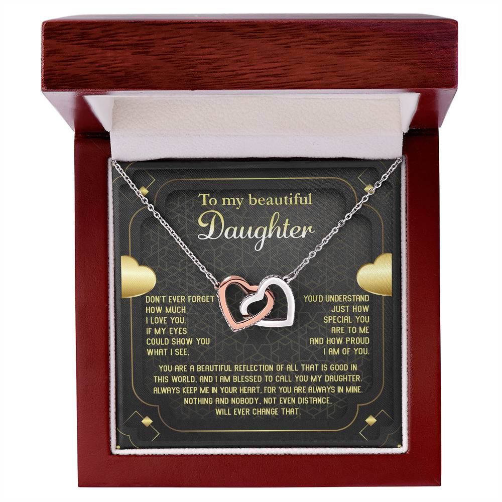 The "To Daughter, Beautiful Reflection - Interlocking Hearts Necklace" features an 18k yellow gold finish and is presented on a card that conveys a heartfelt message of love, pride, and eternal connection. The interlocking hearts are adorned with sparkling cubic zirconia crystals.