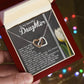 A hand holds an open jewelry box with a Daughter-Heart Love - Interlocking Hearts Necklace in rose gold. Inside, a heartfelt message for a daughter graces the card. Softly blurred colorful lights in the background add magic to the moment.