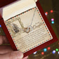 A hand holds the Daughter-Withstand Storm - Interlocking Hearts Necklace, finished in stunning rose gold. The background features a card with an old sailing ship and a motivational message about resilience to a daughter, enhanced by sparkling cubic zirconia crystals.