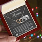 A hand holds an open jewelry box showing a "To Mama To Be, Until We Meet - Interlocking Hearts Necklace" with cubic zirconia crystals. The box reads, "To my Wonderful Mommy" – a unique gift featuring a heartfelt message from "Your Baby Bump.