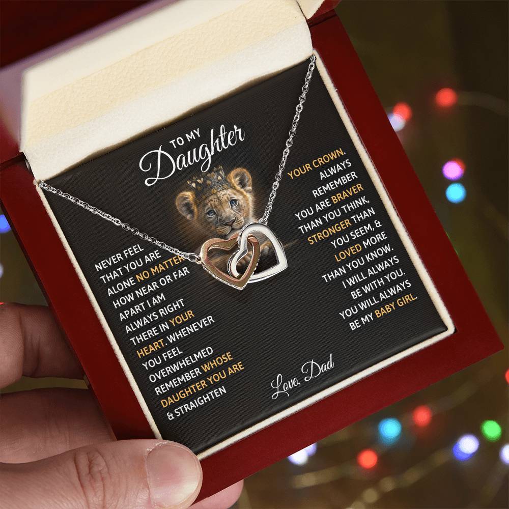 A hand holding a jewelry gift box containing the "To My Daughter, You Will Always Be My Baby Girls - Interlocking Hearts Necklace" with Cubic Zirconia Crystals and an inspirational message from a father to a daughter by ShineOn Fulfillment.