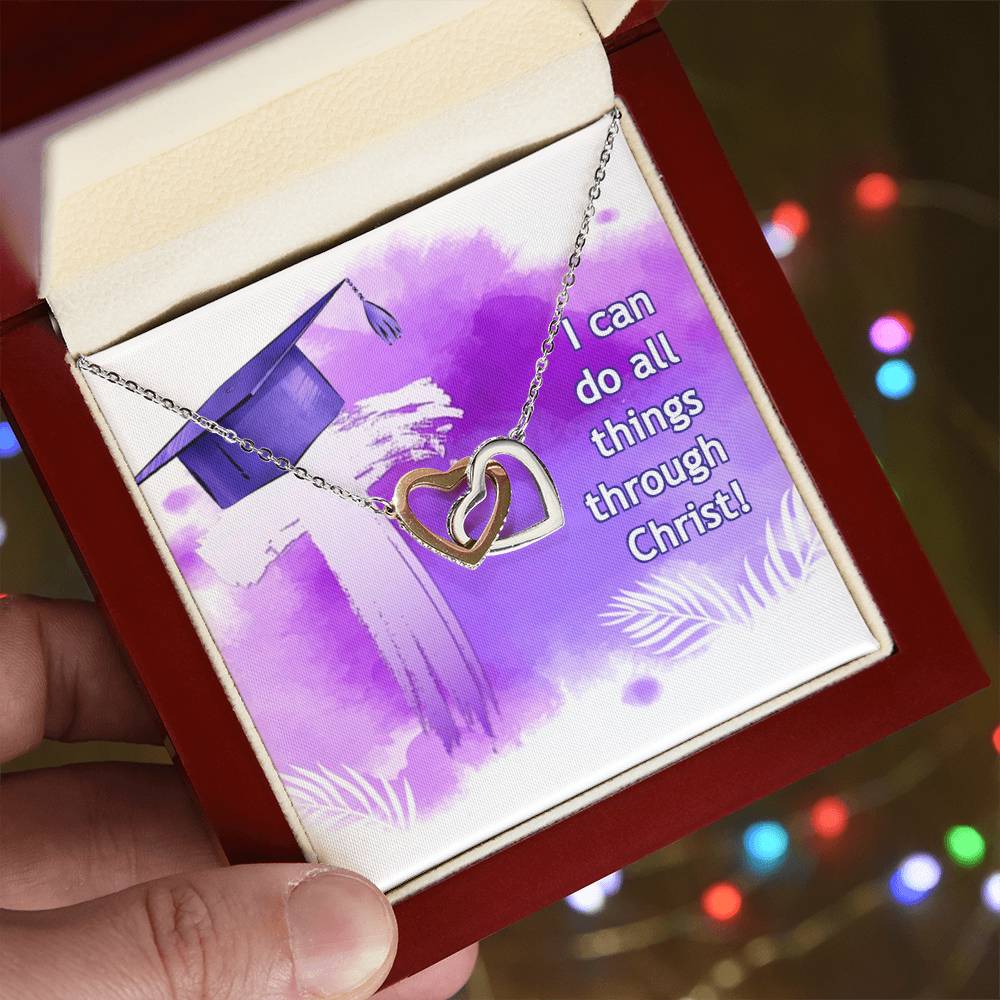 A hand holding a red box with an Anniversary gift; a "I can do all things through Christ" Interlocking Hearts necklace adorned with Cubic Zirconia, featuring a heart pendant, with an inspirational message backdrop from ShineOn Fulfillment.