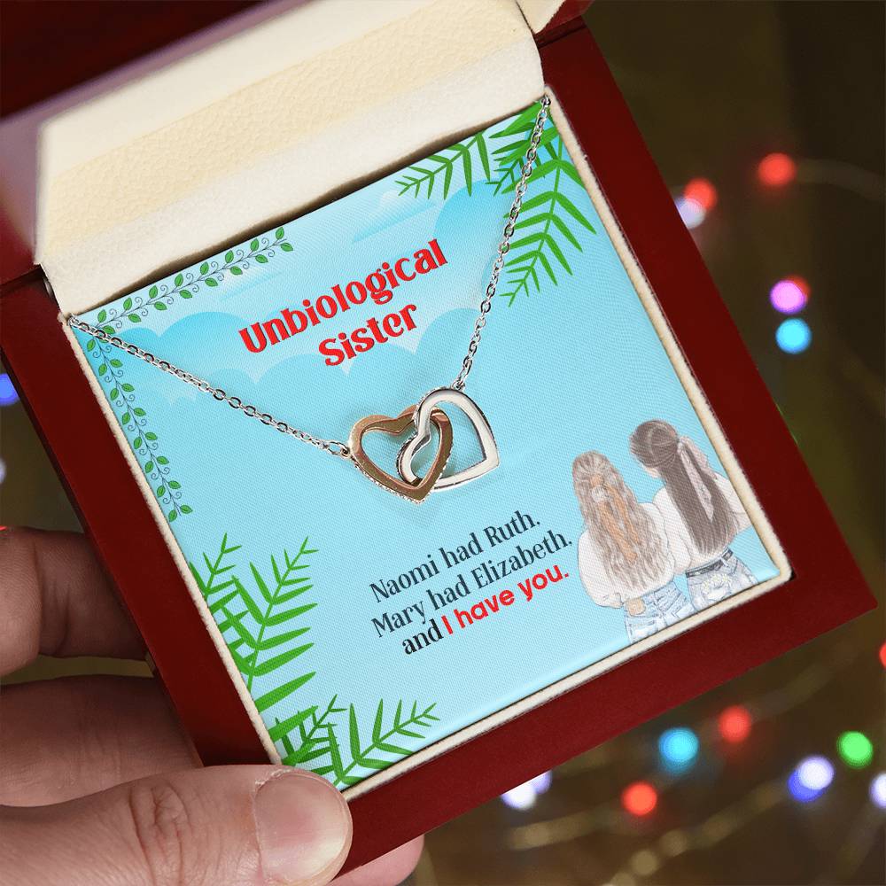 A "To My Unbiological Sister, I Have You" - Interlocking Hearts Necklace by ShineOn Fulfillment featuring two figures is presented in a box with the text "unbiological sister" above personalization.