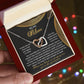 A hand displays an open jewelry box revealing the exquisite Mom-Best Friend - Interlocking Hearts Necklace with a rose gold finish. The backdrop glistens with colorful lights, and inside the lid is a heartfelt message for "My Mom.