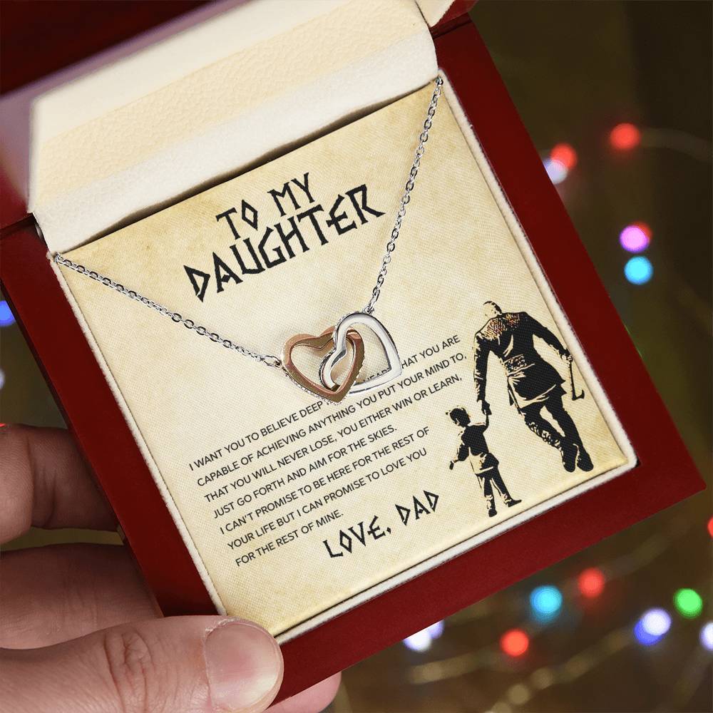 A hand holding a gift box containing a To My Daughter, You Will Never Lose - Interlocking Hearts Necklace with cubic zirconia crystals and a message card addressed to a daughter from a dad by ShineOn Fulfillment.