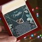 A person holds a jewelry box containing the Daughter-Happiest Person - Interlocking Hearts Necklace, embellished with sparkling cubic zirconia crystals, and featuring an inspirational message for a daughter.