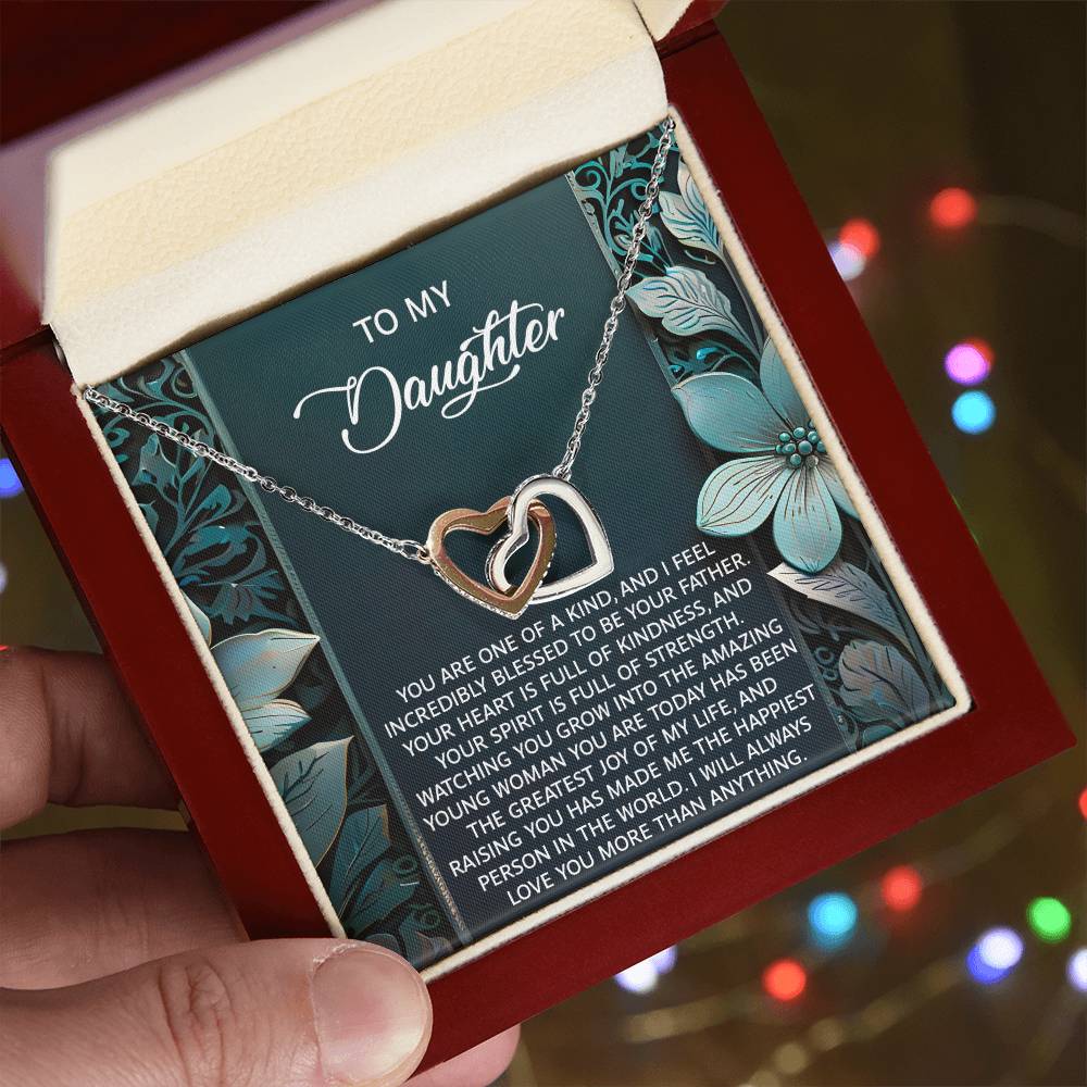 A person holds a jewelry box containing the Daughter-Happiest Person - Interlocking Hearts Necklace, embellished with sparkling cubic zirconia crystals, and featuring an inspirational message for a daughter.