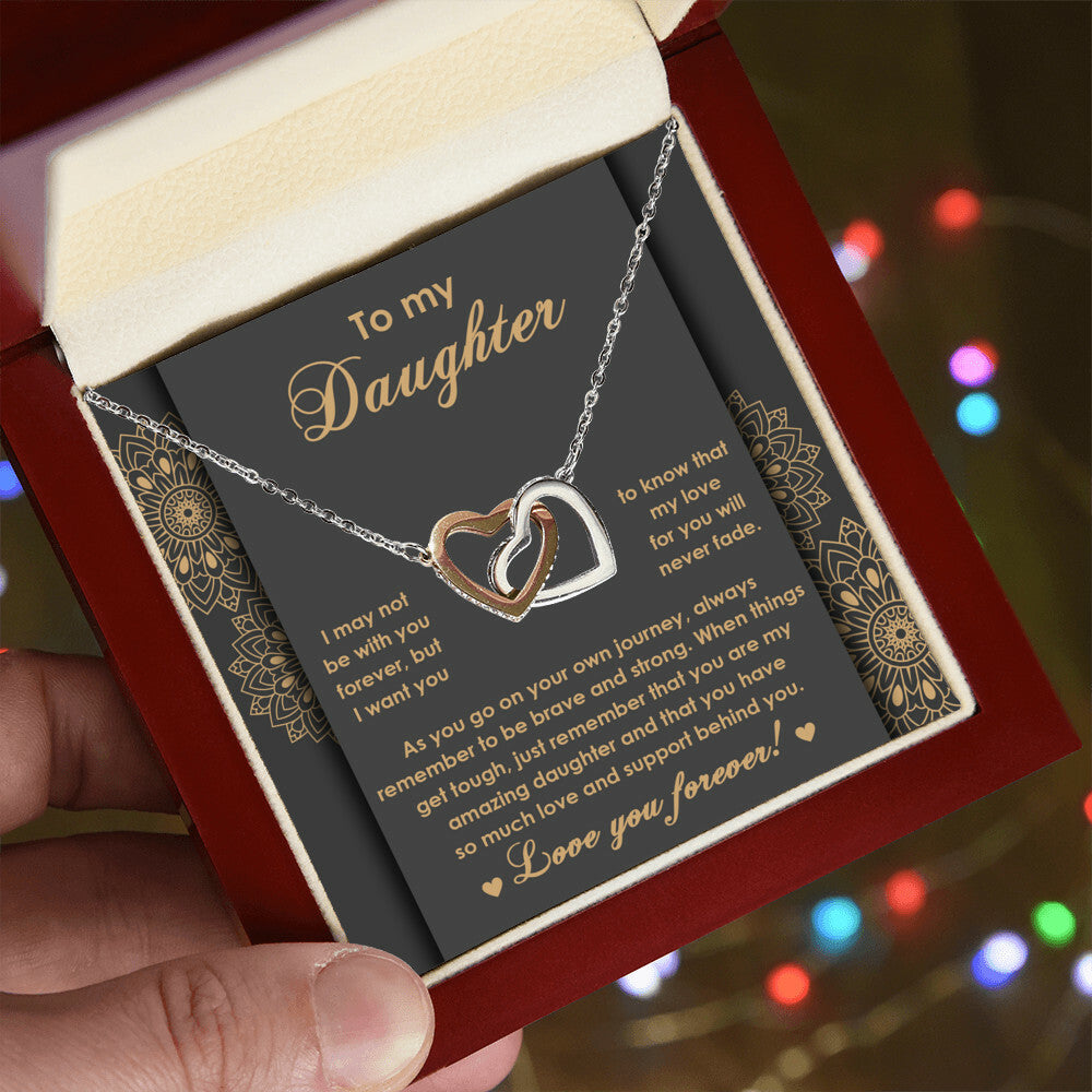 The "To Daughter, Brave And Strong 2 - Interlocking Hearts Necklace" features high-quality polished surgical steel and sparkling cubic zirconia crystals. It is presented on a card adorned with an inspiring message for your daughter, expressing love and encouragement.