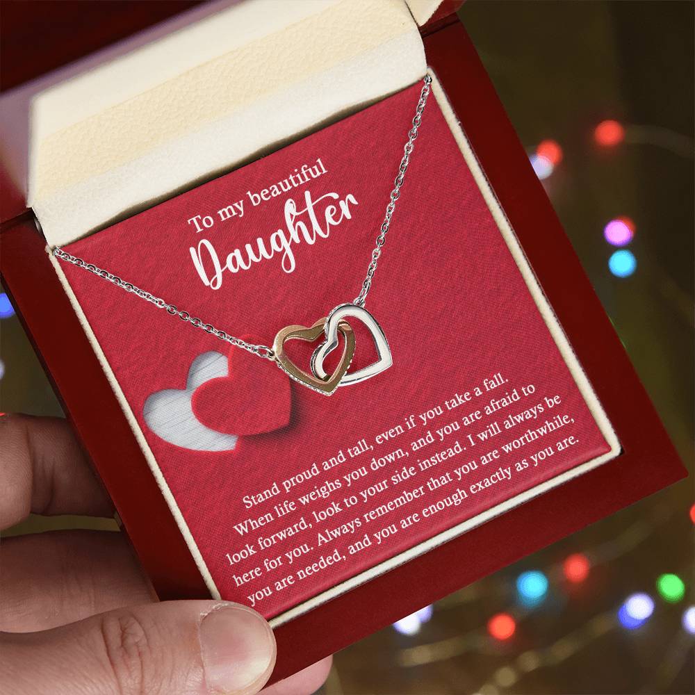 Introducing the elegant "To Daughter, As You Are 2 - Interlocking Hearts Necklace." This stunning piece features two intertwined hearts set against a red background and adorned with sparkling cubic zirconia crystals. The pendant holds the heartfelt message: "To my beautiful Daughter. Stand proud and tall, even if you take a fall..." Crafted from durable surgical steel, this necklace is designed to be both beautiful and enduring.