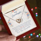 A hand holding a red gift box with a "To My Granddaughter, This Old Woman Will Always Have Your Back" - Interlocking Hearts Necklace adorned with cubic zirconia crystals and a sentimental message from ShineOn Fulfillment to a granddaughter from a grandmother.