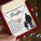A hand presents an open red gift box revealing a Daughter-Smile More - Interlocking Hearts Necklace with a rose gold finish. The box lid features a heartfelt message and a silhouette of an adult and child holding hands, set against colorful, blurred lights.
