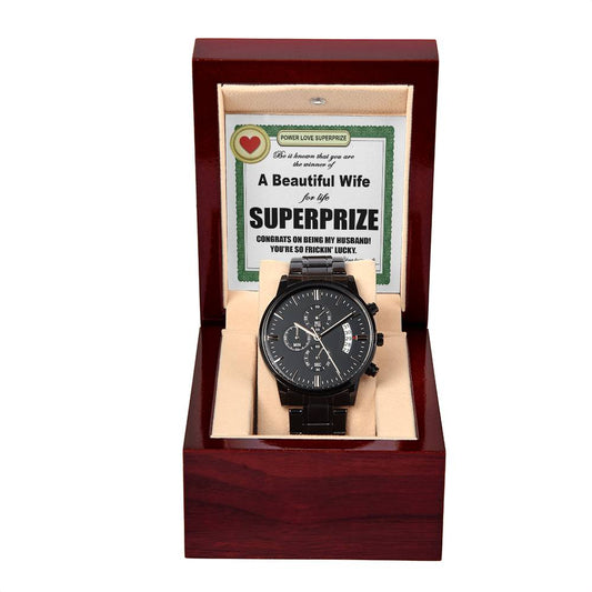 Displayed inside a wooden gift box, the "To Husband, SuperPrize - Metal Chronograph Watch" features a black chronograph design with a luxury copper dial. The interior lid includes a message card that congratulates the husband and lovingly refers to his wife as a "beautiful wife for life" and his "superprize.