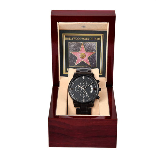 A black chronograph watch with a sleek metal band is displayed in a dark wooden box. The box has a photo of the Hollywood Walk of Fame star in the background, highlighting the "To Father, Walk Of Fame - Metal Chronograph Watch.