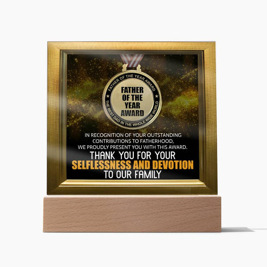 A framed "To Dad, Of The Year - Acrylic Square Plaque" with a gold and black design, recognizing outstanding contributions to fatherhood and expressing gratitude for selflessness and devotion to family. This unique and sentimental gift comes on an LED wooden base, adding a warm glow to its heartfelt message.