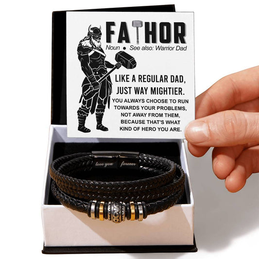 A hand presents an open gift box containing a To Dad-Warrior Dad - Love You Forever Bracelet with metal accents, next to a card describing the word "fathor" as a play on "father" and "Thor.