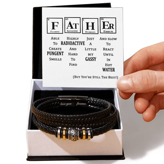 A hand holding a periodic table-inspired card with a humorous "FATHER" message. Below the card, an engraved men's bracelet made of black braided leather with metallic accents, labeled "To Father, Still The Best - Love You Forever Bracelet," is displayed in an open gift box.