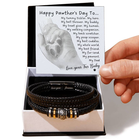 A hand holds a card with a poem titled "Happy Pawther's Day To..." inside a gift box containing an engraved men's bracelet named "To Fur Dad, My Whole World - Love You Forever Bracelet" made of black woven vegan leather with decorative metallic beads.