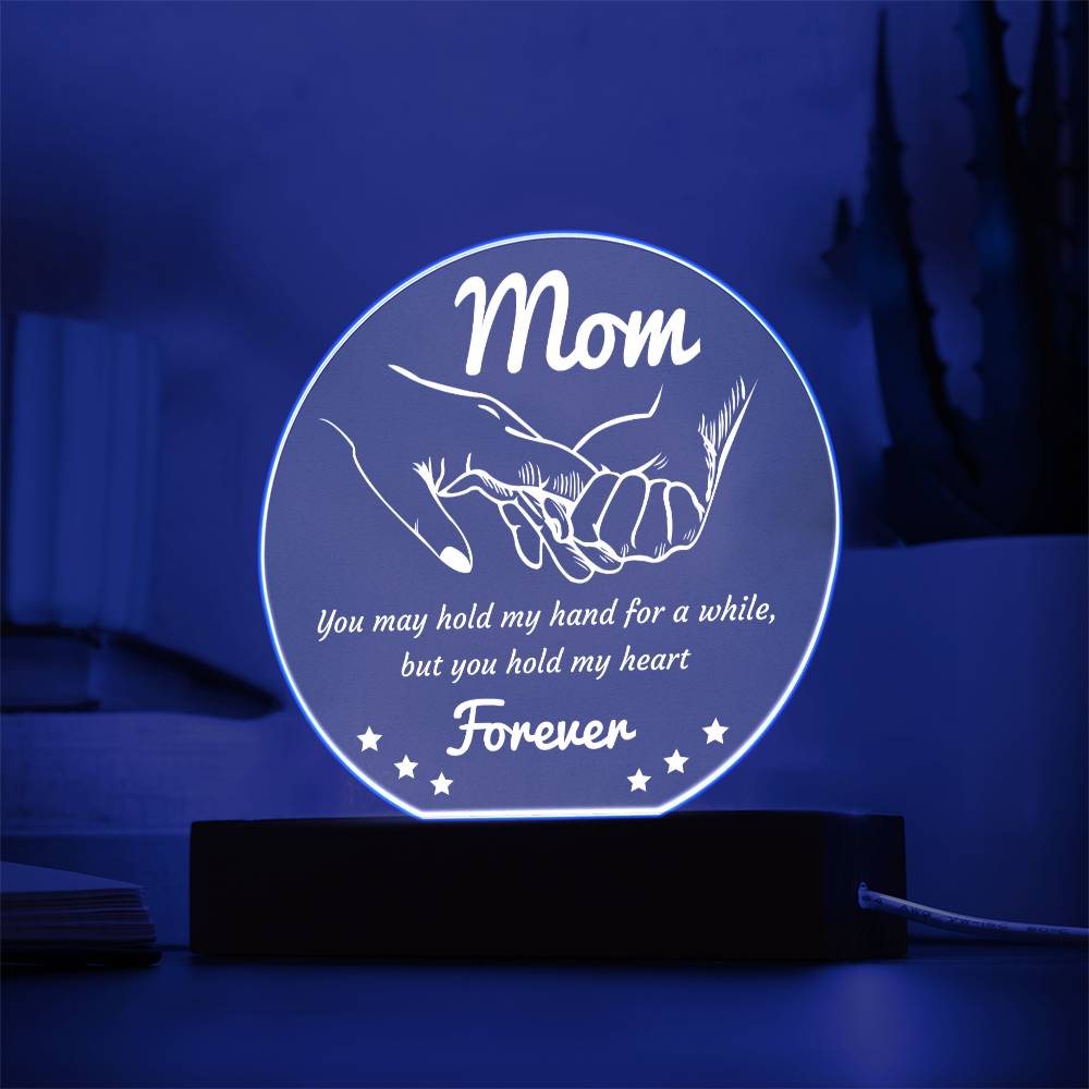 A round, translucent To Mom, Hold My Hand - Acrylic Circle Plaque with subtle etchings, mounted on a rectangular wooden LED base, isolated on a white background.