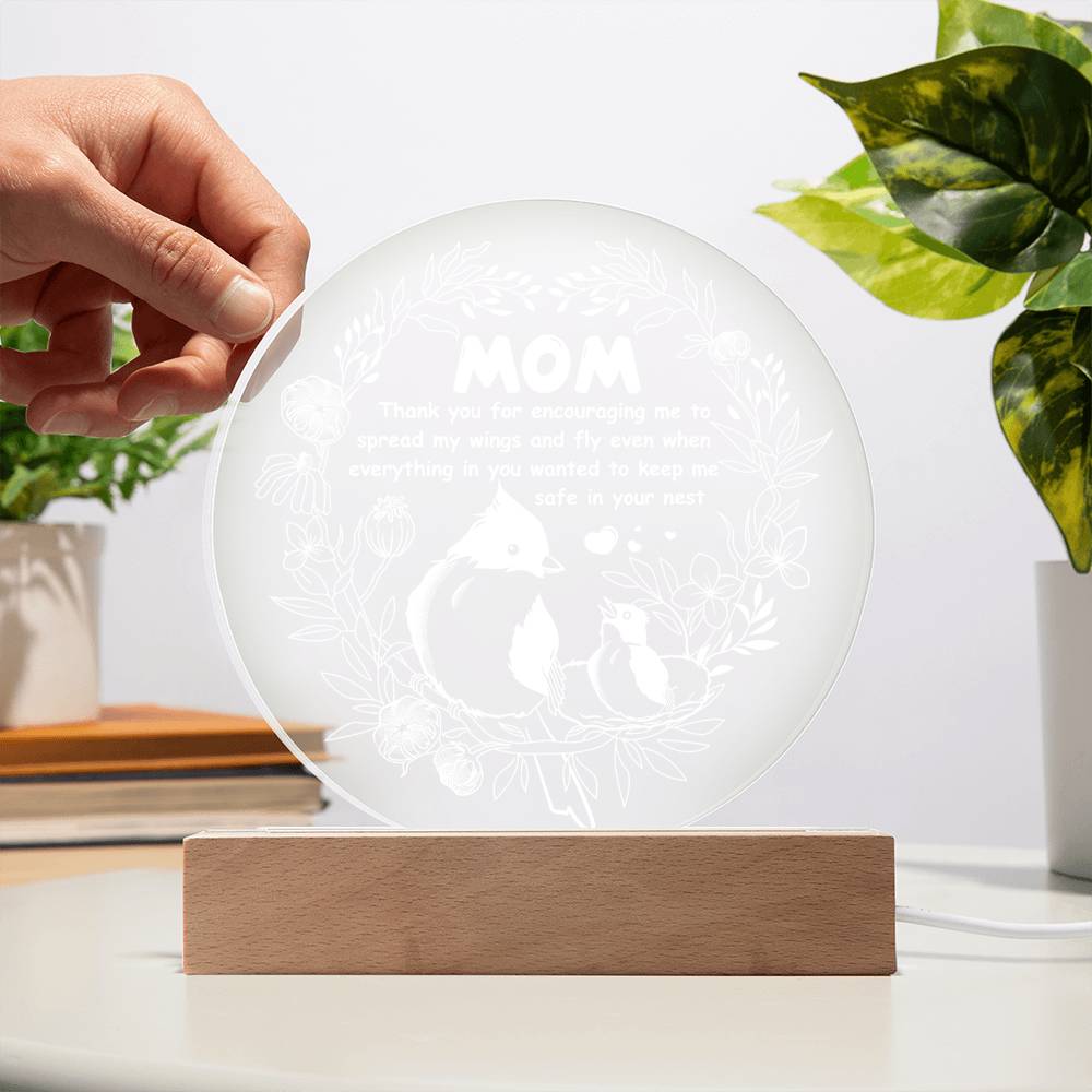 A translucent circular glass plate with a leaf pattern at the edges, displayed upright on a wooden LED base against a white background.