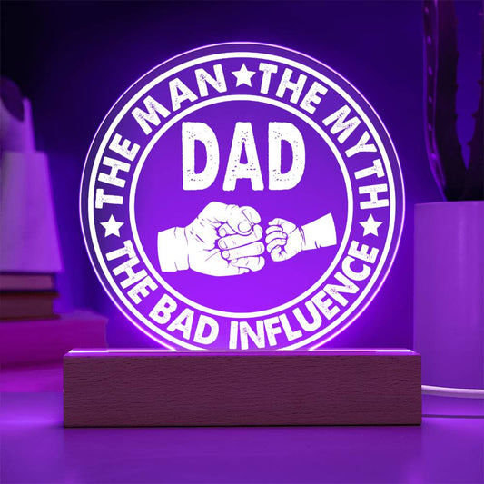 A premium acrylic circular plaque with the text "THE MAN * THE MYTH * THE BAD INFLUENCE" etched around the edge, elegantly mounted on a rectangular wooden LED base, called "To Dad, The Man - Acrylic Circle Plaque".