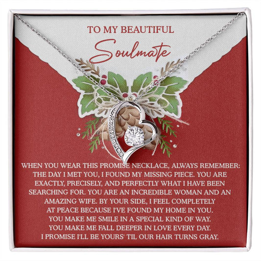 Heart-shaped Soulmate-At Peace - Forever Love Necklace featuring a shimmering CZ crystal, presented in a box with a sentimental message to your soulmate against a red background adorned with floral designs.