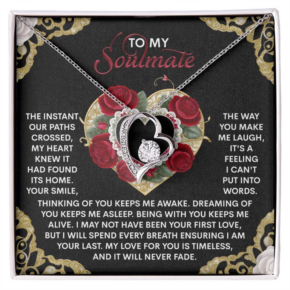 The Soulmate-Never Fade - Forever Love Necklace features a heart-shaped pendant with a CZ crystal, dazzling over a "To My Soulmate" black and gold floral card, showcasing its timeless allure and exquisite gold finish.